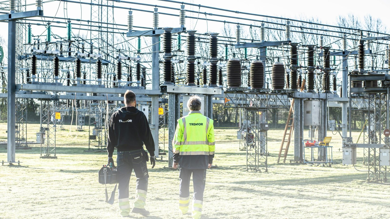 Power Substation & Panels (MCC/PLC) Two workers inspect an outdoor electrical substation, emphasizing safety and maintenance.