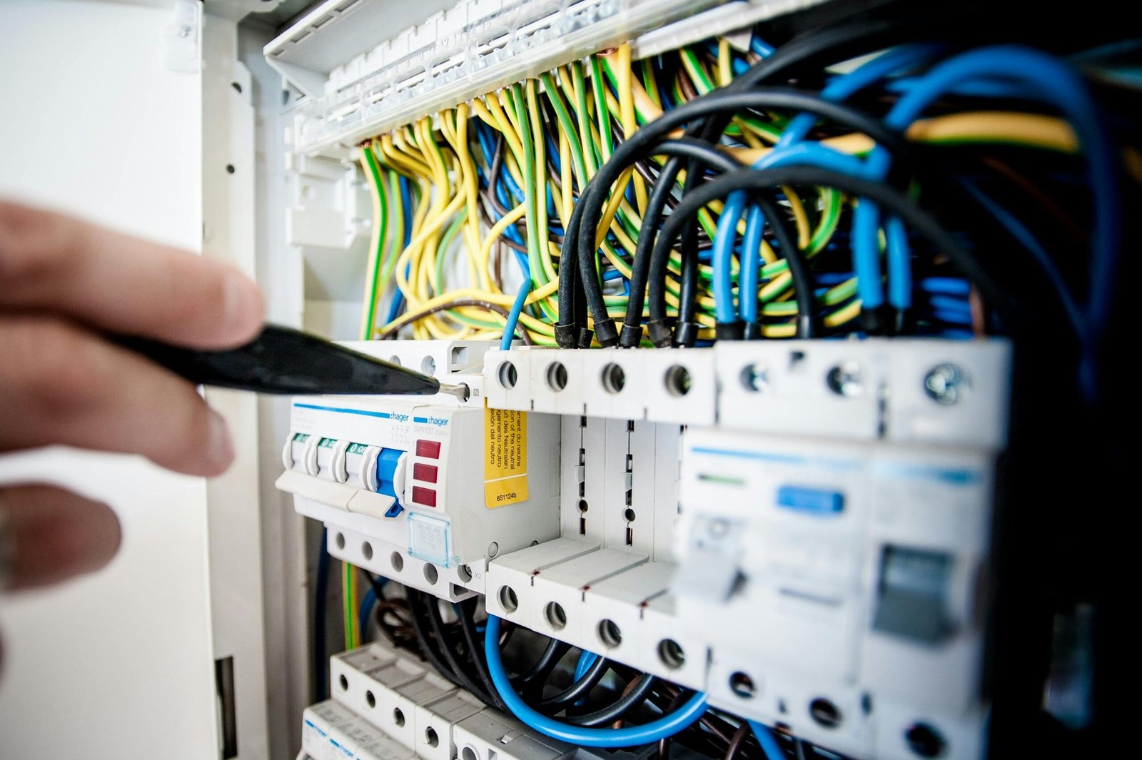 Power Substation & Panels (MCC/PLC) Hand of electrician working on a circuit breaker panel with colorful wires, ensuring safe electrical connections.