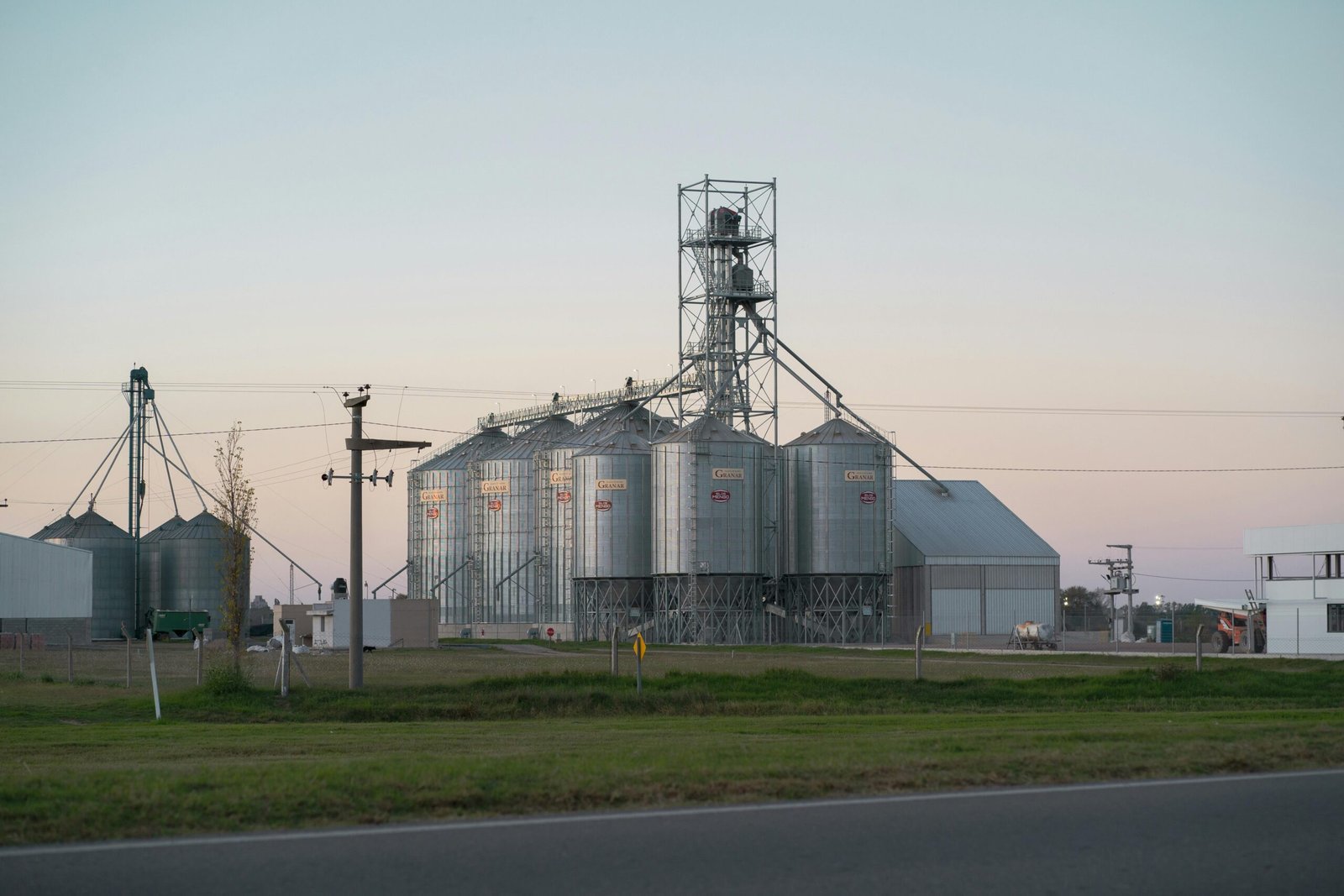 Grain Silo & Handling Equipment Metal grain silos alongside rural road in Hernando, Córdoba, Argentina at dusk.